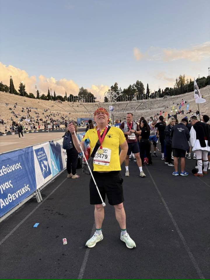 Richard with a big smile on his face after the marathon, proudly wearing his medal and holding up his cane
