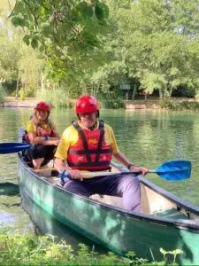 Darren and Suzie in a canoe with lush greenery all around them.