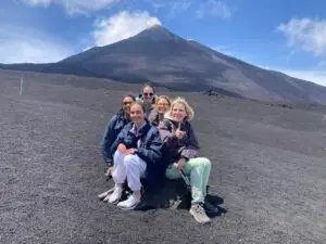 Group photo of Zehra, Kristina, Suzie, Bushra and Noemi on mount Etna, behind us is the peak