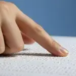 A hand with a pointed finger reading braille.